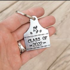 a hand holding a metal keychain that says class of 2012