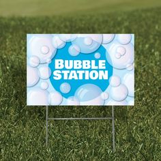 a bubble station sign in the middle of some green grass with water droplets on it