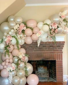 a fireplace decorated with balloons, flowers and greenery