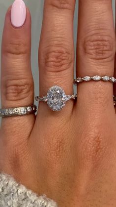 a woman's hand with three different rings on her fingers and one ring in the middle