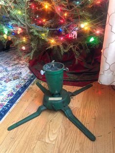 a christmas tree is in the background with lights on it and a small green machine