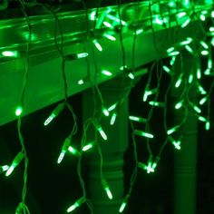 green christmas lights are hanging from the side of a bench