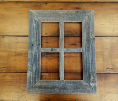 an old window is hanging on the wall in front of a wood paneled wall