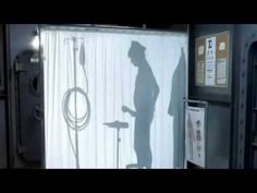 the shadow of a man standing in front of a shower curtain next to a sink