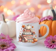 a coffee mug with a pink frosting on it next to flowers and pumpkins