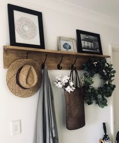 a wall mounted shelf with two hats and three coats hanging from it's hooks