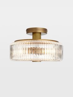 a semi - flush ceiling light fixture with clear glass and brass finish, on a white background