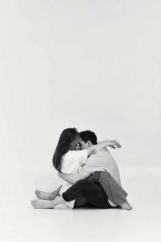 two people sitting on the ground hugging each other