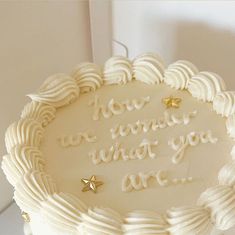 a birthday cake with white frosting and gold stars on the top that says, how do you want what you are?