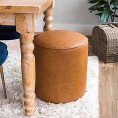 a wooden table sitting on top of a white rug next to a blue chair and footstool