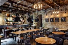 an empty restaurant with wooden tables and chairs in front of the counter, along with hanging lights