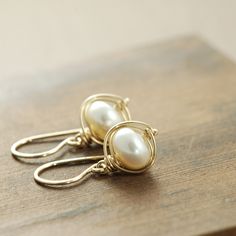 Lustrous white pearls are wrapped with 14k gold filled wire in these simple yet stunning earrings. These are extremely versatile and are easily dressed up or down. I love how the wire frames the luminous pearls... This is one of my favorite styles. The earrings fall a little over 1 inch (2.6 cm) from the very tops of the earwires and are about 7/16 inch (1.1 cm) at their widest points. Pearls are June's birthstone, so these make a great gift for someone with a birthday or anniversary in that mon Yellow Gold Wire Wrapped Pearl Earrings Gift, Wire Wrapped Yellow Gold Pearl Earrings Gift, Elegant Gold Wire Wrapped Wrap Earrings, Delicate Wire Wrapped Yellow Gold Earrings, Everyday Gold Wire Wrapped Pearl Earrings, Delicate Yellow Gold Wire Wrapped Earrings, Elegant Wire Wrapped Wrap Earrings As Gift, Gold Wire Wrapped Pearl Earrings For Gift, Elegant Wire Wrapped Earrings For Everyday