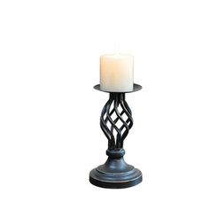 a white candle sitting on top of a metal stand with a lit candle in it