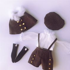 doll clothes and accessories are laid out on a white surface, including a brown hat