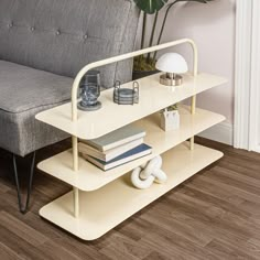 a couch and some books on a shelf near a table with a lamp in it