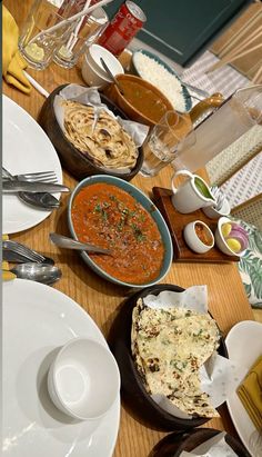 a wooden table topped with lots of plates and bowls filled with different types of food