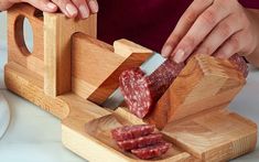 a person cutting up some meat on a wooden board