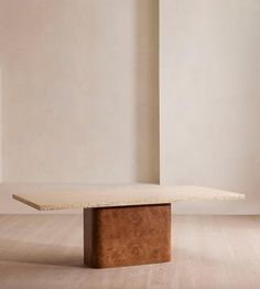 a wooden table sitting on top of a hard wood floor next to a white wall