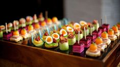 an assortment of appetizers are arranged on a table with toothpicks and fruit