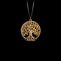 a gold pendant with a tree on it's side and leaves in the middle