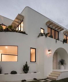 a white house with plants on the windows and steps leading up to it's entrance