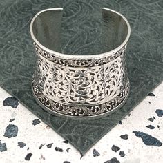 Indulge In The Timeless Elegance Of This Lois Hill Statement Cuff Bracelet. The Center Section Proudly Showcases Lois Hill's Signature Scroll Design, While The Borders Are Adorned With The Intricate Granulated Pattern. The Cuff Edges, Border, And Entire Backside Are All Hammered. Stamped With "Lois Hill" And A Floral Logo Above It At The Center Back, This Bracelet Embodies Authenticity And Artistry. With An Inside Measurement Of Nearly 5.75" And A Gap Of 1.25", The Total Inside Circumference Spans Nearly 7". The Width At The Widest Point, Measured From The Back, Is Just Over 2.125". With A Total Weight Of 123 Grams, This Bracelet Is A Wearable Masterpiece. Product Details: Decade: 20 Lois Hill Jewelry, Statement Cuff Bracelet, Artistic Aesthetic, Floral Logo, Scroll Design, Fine Jewelry Bracelets, Ostrich Feathers, Swirl Pattern, Womens Jewelry Bracelets