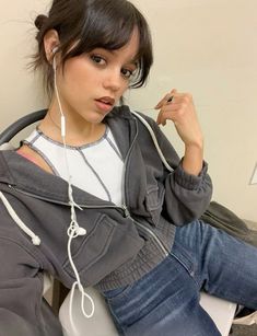 a young woman sitting on top of a toilet wearing headphones and listening to music