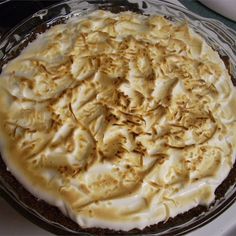 a pie with white frosting sitting on top of a glass pan covered in icing