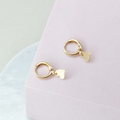 Experience the charm of our Dainty Heart Hoops Earrings, a delightful blend of elegance and whimsy. These earrings feature delicate heart-shaped designs that dangle gracefully from sleek gold hoops, adding a touch of romance to your look. Perfect for any occasion, our Heart Charm Hoops are versatile enough to complement both casual and formal outfits. Their lightweight and comfortable design makes them ideal for all-day wear, ensuring they become a cherished addition to your jewelry collection. Elegant Hoop Heart Charm Earrings, Elegant Dangle Huggie Earrings With Heart Charm, Valentine's Day Heart Charm Dangle Huggie Earrings, Valentine's Day Huggie Dangle Earrings With Heart Charm, Minimalist Dangle Hoop Earrings For Valentine's Day, Valentine's Day Dangle Huggie Earrings With Heart Charm, Dainty Hoop Earrings For Valentine's Day, Elegant Double Heart Huggie Earrings With Heart Charm, Dainty Heart Charm Hoop Earrings