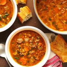 three bowls of soup with bread on the side