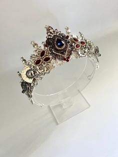 One of a kind ornate vintage style crown.  A great unique accessory for brides, parties or any special occasion.  Crafted with the utmost care, this silver and diamanté crown is made out of a strong alloy base with lots of sparkly crystals, silver filigree and assents of mahogany red and blue jewels and embellishments. This silver tiara exudes elegance and sophistication, making it a perfect accessory for parties and special occasions.  Once size, best fitted to the back of the head and held in place with clips.  Only one of these made!  Includes bobby pins to keep it in place and also packaged ready to give as a gift. Fantasy Crowns, Queen Crowns, Elegant Gold Necklace, Crown Accessories, Jewelled Headpiece, Slytherin Fashion, Fantasy Crown, Crystal Crown Tiaras, Sparkly Crystals