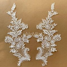 two pieces of white lace with flowers and leaves on them are sitting on a brown surface