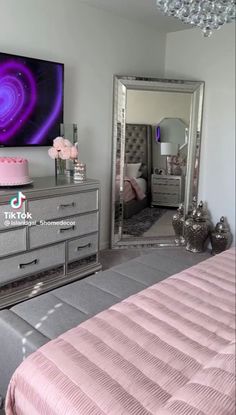 a bedroom decorated in pink and silver with a large mirror on the wall above it