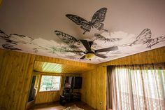 a ceiling fan with butterflies painted on it in a room that has wood paneling