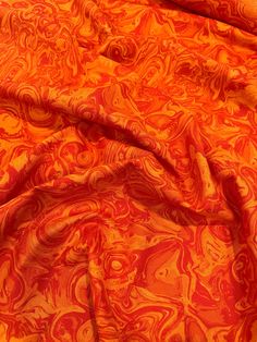 an orange and red fabric with swirls on it's surface, as well as the background