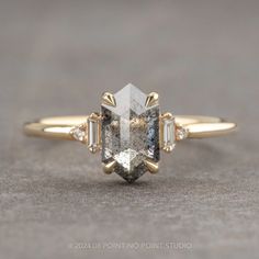 a yellow gold engagement ring with an unusual cut diamond surrounded by three baguets