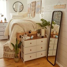 a bedroom with a bed, dresser and mirror on the wall next to each other