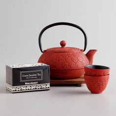 a red teapot and cup sitting on a table next to a box of matches