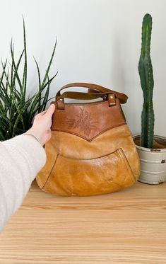 Vintage 60s two tone brown leather tooled shoulder bag.  Features a pocket on the outside and a zippered pocket inside. Two Tone Leather Bag, Retro Vintage Brown Bag With Leather Backing, Vintage Hand Tooled Tote Satchel, Vintage Hand-tooled Tote Satchel, Vintage Style Hand Tooled Tote Satchel, Vintage Leather-backed Tote Bag, Vintage Tote Bag With Leather Backing, Retro Hand-tooled Satchel Shoulder Bag, Retro Hand Tooled Satchel Shoulder Bag