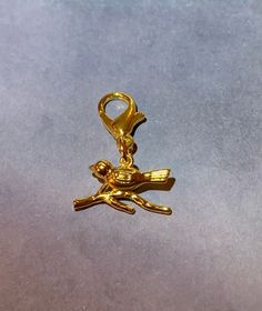 a gold charm with a bird on it sitting on a gray surface next to a pair of scissors