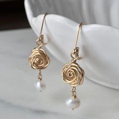 The Rose is a timeless symbol of love and beauty! Handcrafted Rose and Pearl Dangle Earrings will coordinate nicely with your pearl necklace - perfect for special occasion or everyday!  :: DETAILS :: ♥ Delicate handmade Rose connectors  measure approximately 1/2" in diameter and are handcrafted of 14K Gold fill, 14K Rose Gold fill, or Sterling Silver.  Each pair will vary slightly due to their handcrafted nature.   ♥ Freshwater Pearl dangles add interest and length for a total earring length of approximately 1 5/8". ♥ Leverback earwires are shown but French Hooks are available as an option in the drop down menu; hooks come with earring stops to provent loss.  All metals are 14K Gold fill, 14K Rose Gold fill, or Sterling Silver; heirloom quality. ♥ Arrives in a logo gift box with artist sig Elegant Rose Jewelry For Mother's Day, Rose Colored Dangle Jewelry With Rose Design, Gold Rose Earrings For Gift, Rose Gold Rose Detail Wedding Earrings, Elegant Flower Shaped Earrings With Roses, Elegant Rose Flower Earrings For Gift, Elegant Rose Earrings For Mother's Day, Elegant Rose Gold Earrings With Roses, Elegant Rose Design Earrings For Gift