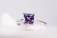 This beautiful ring features a princess cut, square shape, purple sapphire with a slight color change from lavender purple to a warm amethyst tone. The alluring created sapphire is set on a embellished mount and a dainty band of minimalist elegance. Made in sterling silver, rhodium plated for extra long-lasting shine. Dimensions -6mm square, princess-cut sapphire -Band: 1.8mm -Stone mount from band to top: 6.5mm (above the finger) -Saturation: Highly-saturated purple -Hardness: 9 on the Mohs Har Elegant Purple Sapphire Solitaire Ring, Elegant Purple Solitaire Sapphire Ring, Elegant Asscher Cut Purple Ring, Elegant Purple Asscher-cut Ring, Elegant Purple Asscher Cut Ring, Elegant Amethyst Princess Cut Ring For Anniversary, Elegant Princess Cut Amethyst Ring For Anniversary, Elegant Princess Cut Amethyst Ring For Formal Occasions, Purple Princess Cut Ring For Anniversary