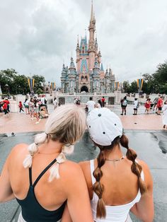 two women are sitting in front of a castle with their backs turned to the camera