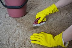 a person in yellow gloves is cleaning the carpet