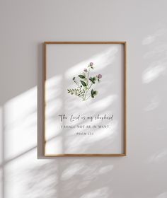 a white wall with a wooden frame hanging on it's side next to a plant