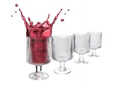 three wine glasses with red liquid splashing out of the top, and one is empty