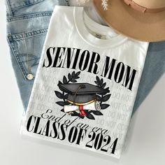 Senior Class Of 2024/Senior Mom Class Of 2024 Tee Graphic Design: The pattern of this t-shirt features a bold graphic design, making it stand out from other regular tees. Crew Neckline: The crew neckline adds a classic touch to the casual, fashion-forward style of this t-shirt. Casual Occasion: Perfect for casual occasions such as hanging out with friends or running errands, the Senior Class Of 2024/Senior Mom Class Of 2024 Tee is an essential addition to your wardrobe. Fits All Sizes: Available Black T-shirt With Graphic Print For Graduation, Black Graphic Print T-shirt For Graduation, Graduation T-shirt With Letter Print In Relaxed Fit, Custom Print Cotton Tops For Graduation, Graphic Tee Tops With Graphic Print For Graduation, Tee Graphic Design, Plainfield Illinois, Senior Class Of 2024, Bold Graphic Design