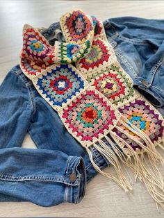 a crocheted scarf is laying on the floor next to some denim jacket and jeans