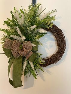 a wreath with green and white flowers hanging on a wall