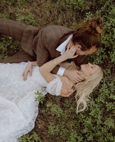 two people laying in the grass with their heads touching each other's foreheads